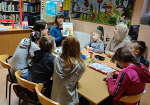 Pani bibliotekarka prezentuje dzieciom książkę