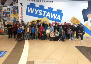 Pamiątkowe zdjęcie uczestników wycieczki na tle napisu "Największa w Europie wystawa"