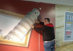 Uczeń pozuje przy ścianie "podtrzymując" przewracającą się wieżę