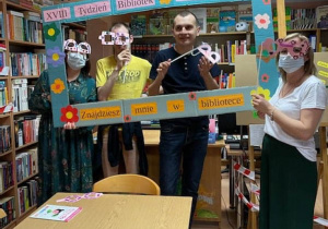 Uczestnicy Rehabilitacja 25 plus w Bibliotece Miejsckiej w Radomsku patrzą przez różowe okulary w dużej ramce z okazji XVIII Tygodnia bibliotek.